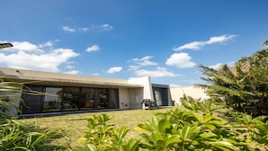 Una casa moderna con ventanas amplias, fachada de concreto y césped cuidado.