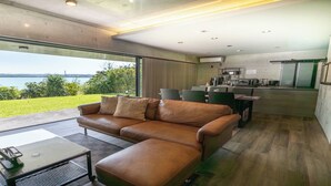 Eine moderne Küche mit Blick ins Freie, ein Ledersofa und ein Essbereich.