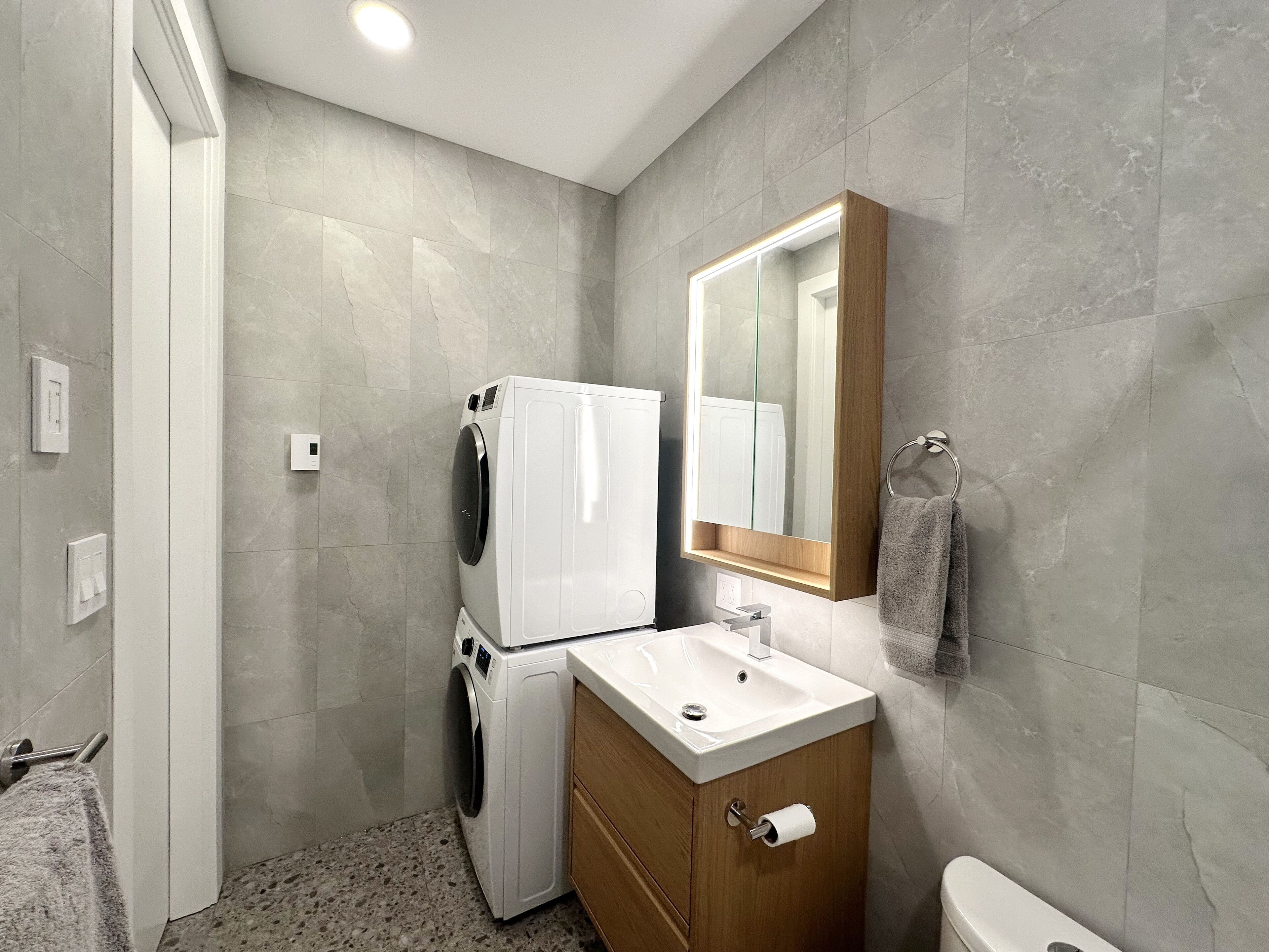 Ein kleines Badezimmer mit Waschmaschine, Waschbecken und Toilette.