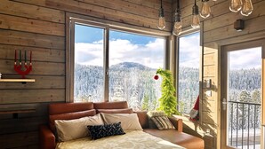 A bedroom with a bed, a wooden ceiling, and large windows overlooking a snowy forest. - Sunset Lodge - Modern Mountain Luxury - Epic Views - Sleeps 6 (Comox Valley C (Puntledge-B*)