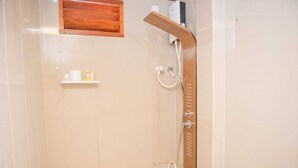 A bathroom with a shower, a toilet, and a shelf with toiletries. - Avanti retreat  (Vaadhoo)