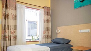 A hotel room with two beds, a wooden headboard, a window with curtains, and a wall-mounted power outlet. - Avanti retreat  (Vaadhoo)