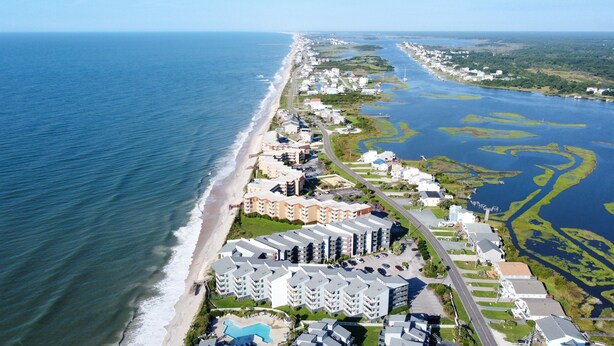 An aerial view of a coastal hotel with multiple buildings, a beach, and a marina.
