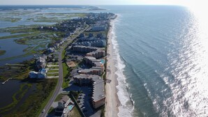 An aerial view of a coastal hotel with multiple buildings, a beach, and surrounding wetlands.