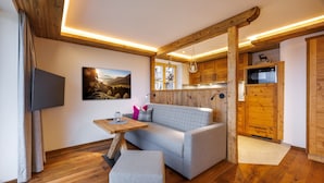 A modern living room with a grey sofa, wooden flooring, and a wooden ceiling structure. - Kienberg 50 sqm, balcony or terrace, kitchen, 1 bedroom, 1 bed-sitting room, WLAN (Ruhpolding)