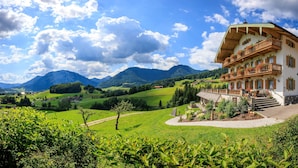 A traditional chalet with a balcony, surrounded by lush green fields and mountains in the background. - Kienberg 50 sqm, balcony or terrace, kitchen, 1 bedroom, 1 bed-sitting room, WLAN (Ruhpolding)