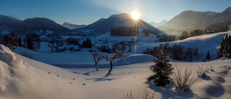 A snowy landscape with a clear sky and mountains in the background.