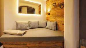 A cozy corner with a cushioned bench, a wooden wall panel, and a mirror with a light above it. - Zellerberg 45 to 50 sqm, balcony, kitchen, 1 bedroom, living room, 4 pers, WLAN (Ruhpolding)