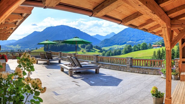 A terrace with wooden furniture and green umbrellas, overlooking a mountainous landscape. - Zellerberg 45 to 50 sqm, balcony, kitchen, 1 bedroom, living room, 4 pers, WLAN (Ruhpolding)