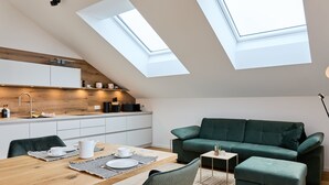 Un loft moderno con comedor, kitchenette y un sofá verde.