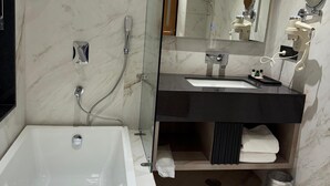 Un baño moderno con una bañera grande, ducha con cerramiento de vidrio y tocador con espejo y secador de pelo.