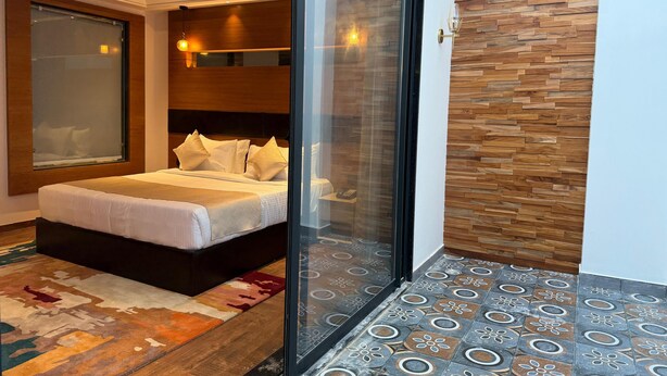 Un dormitorio moderno con una cama grande, una puerta de vidrio que da a un balcón y un suelo con diseño.