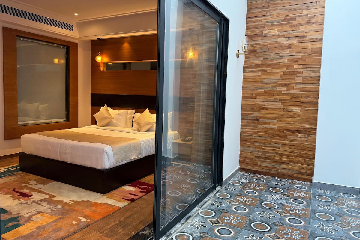 Um quarto moderno com uma cama grande, porta de vidro para uma varanda e piso estampado.
