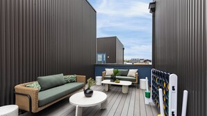 A modern outdoor patio with wicker furniture, a round table, and a pool table.