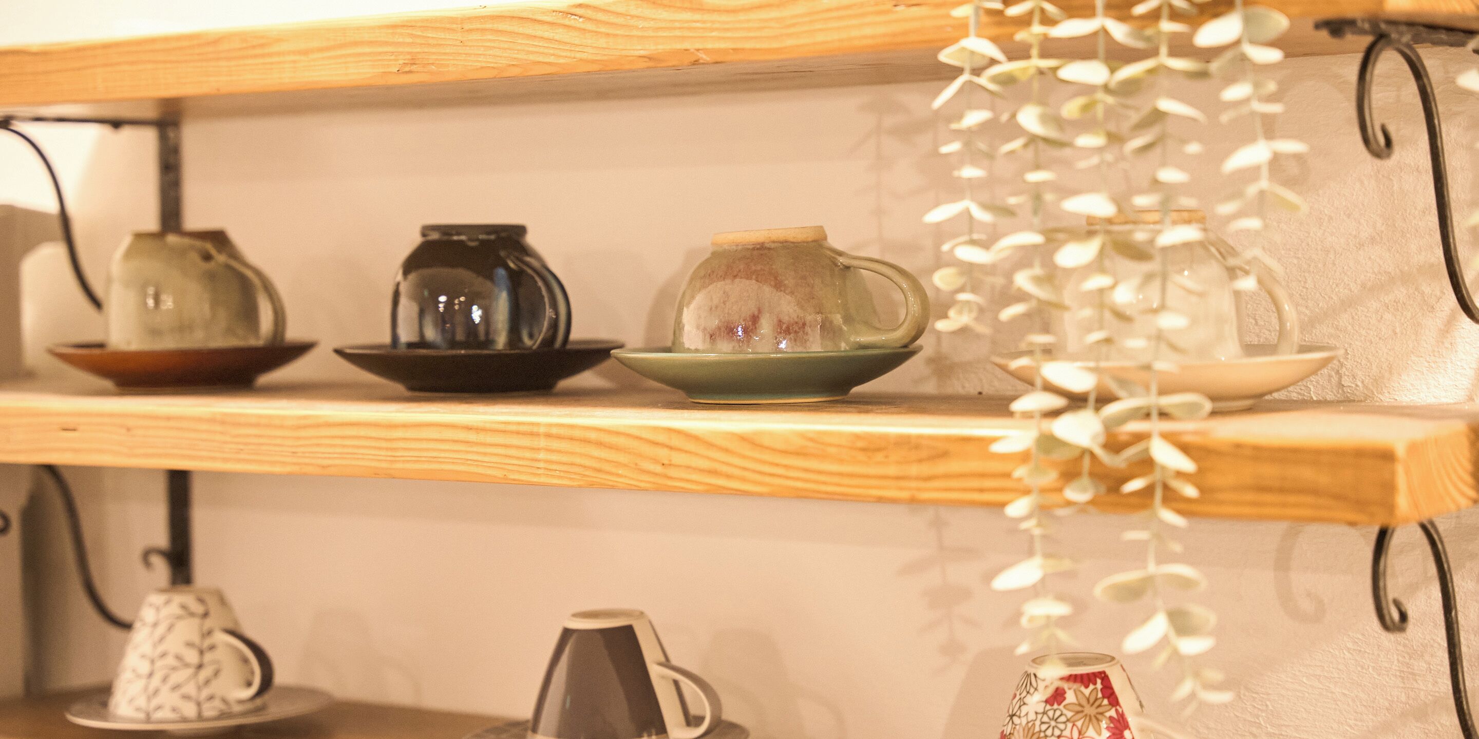 A shelf with various ceramic items including a teapot, a coffee pot, and a bowl.