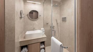 Un baño moderno con lavamanos, espejo y ducha.
