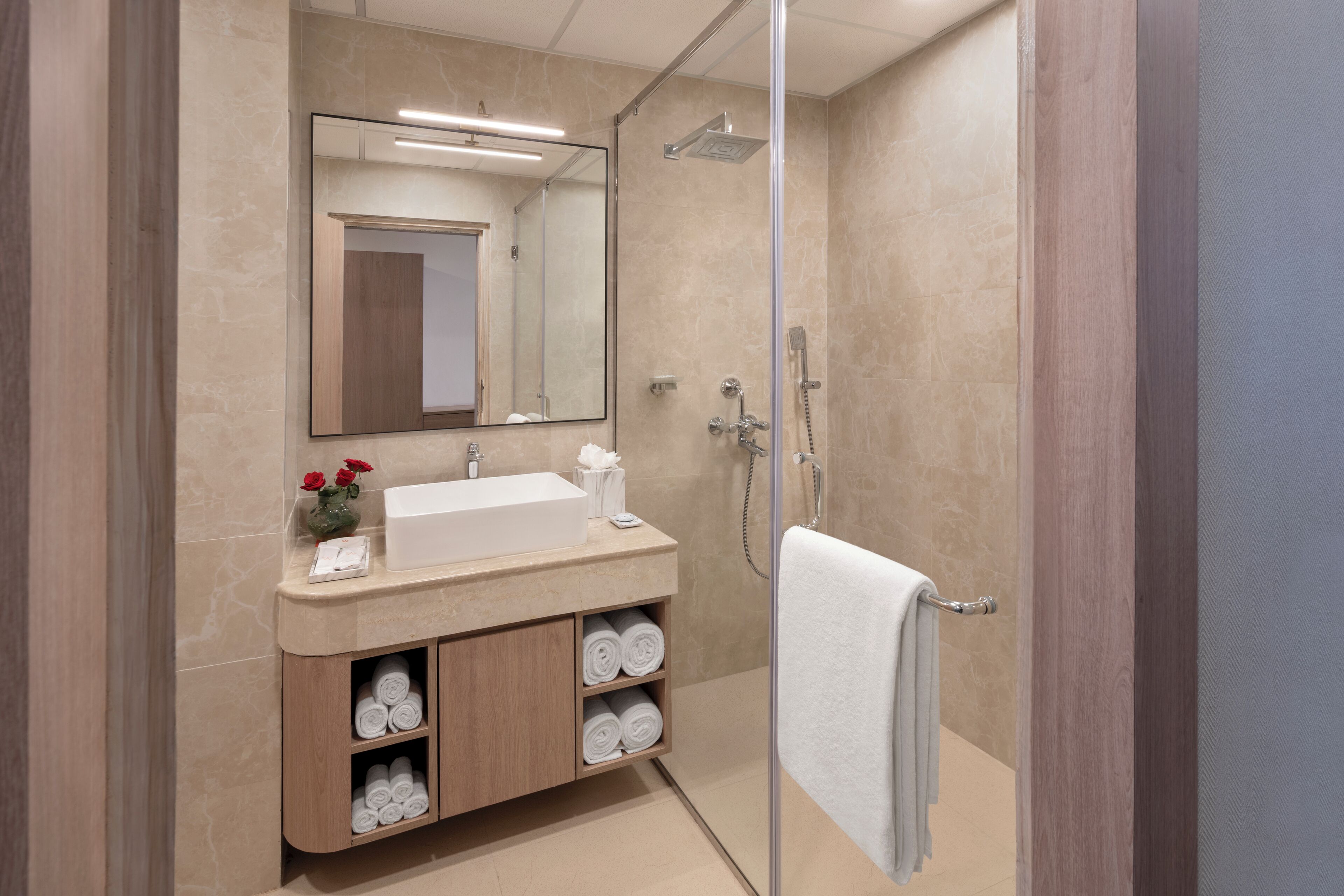 A modern bathroom with a large mirror, a sink, and a shower.