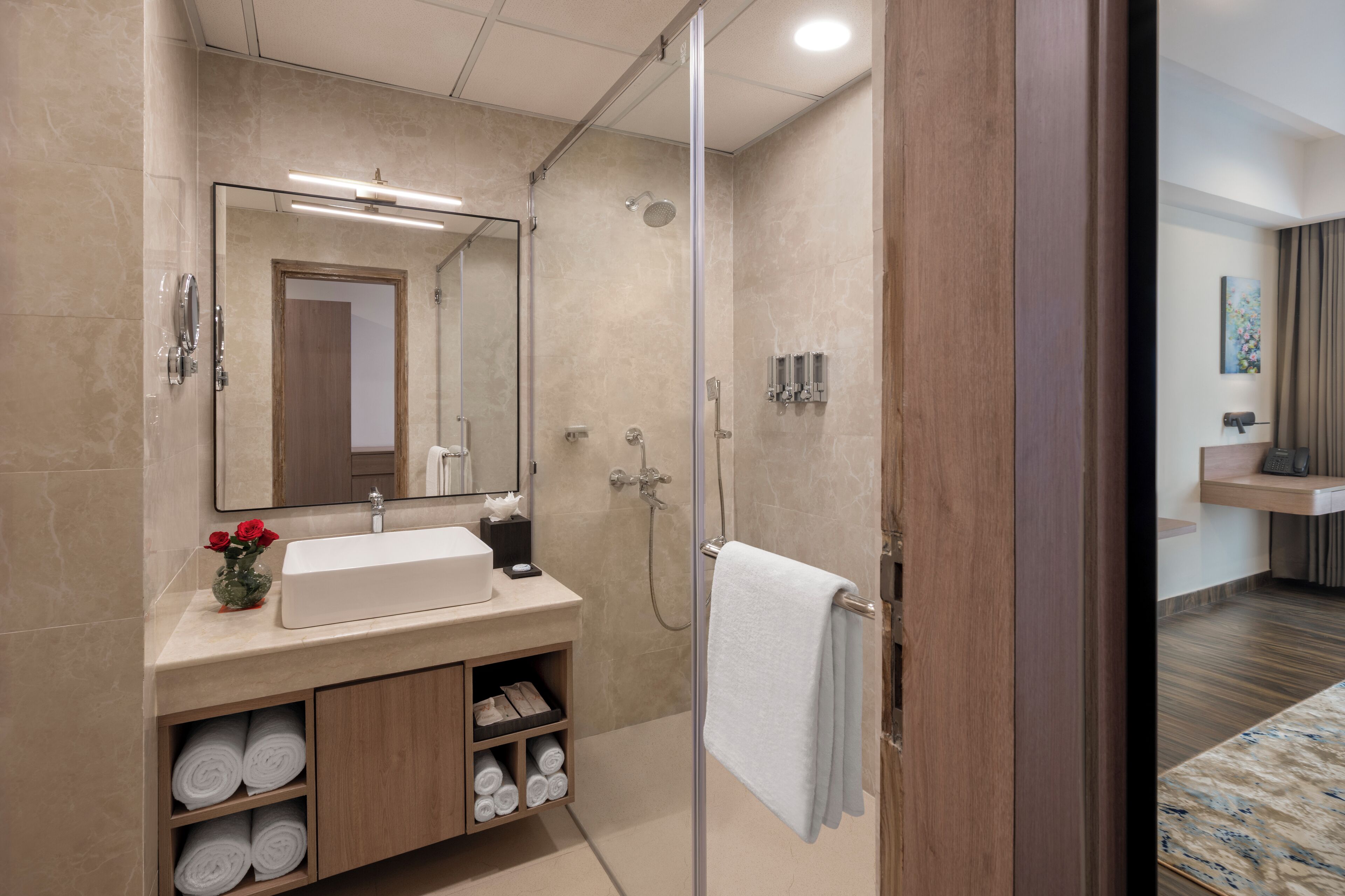 Une salle de bain moderne avec une douche à parois de verre, un lavabo avec un miroir et des serviettes soigneusement pliées.