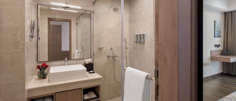 Un baño moderno con cabina de ducha de vidrio, un lavabo con espejo y toallas ordenadamente dobladas.