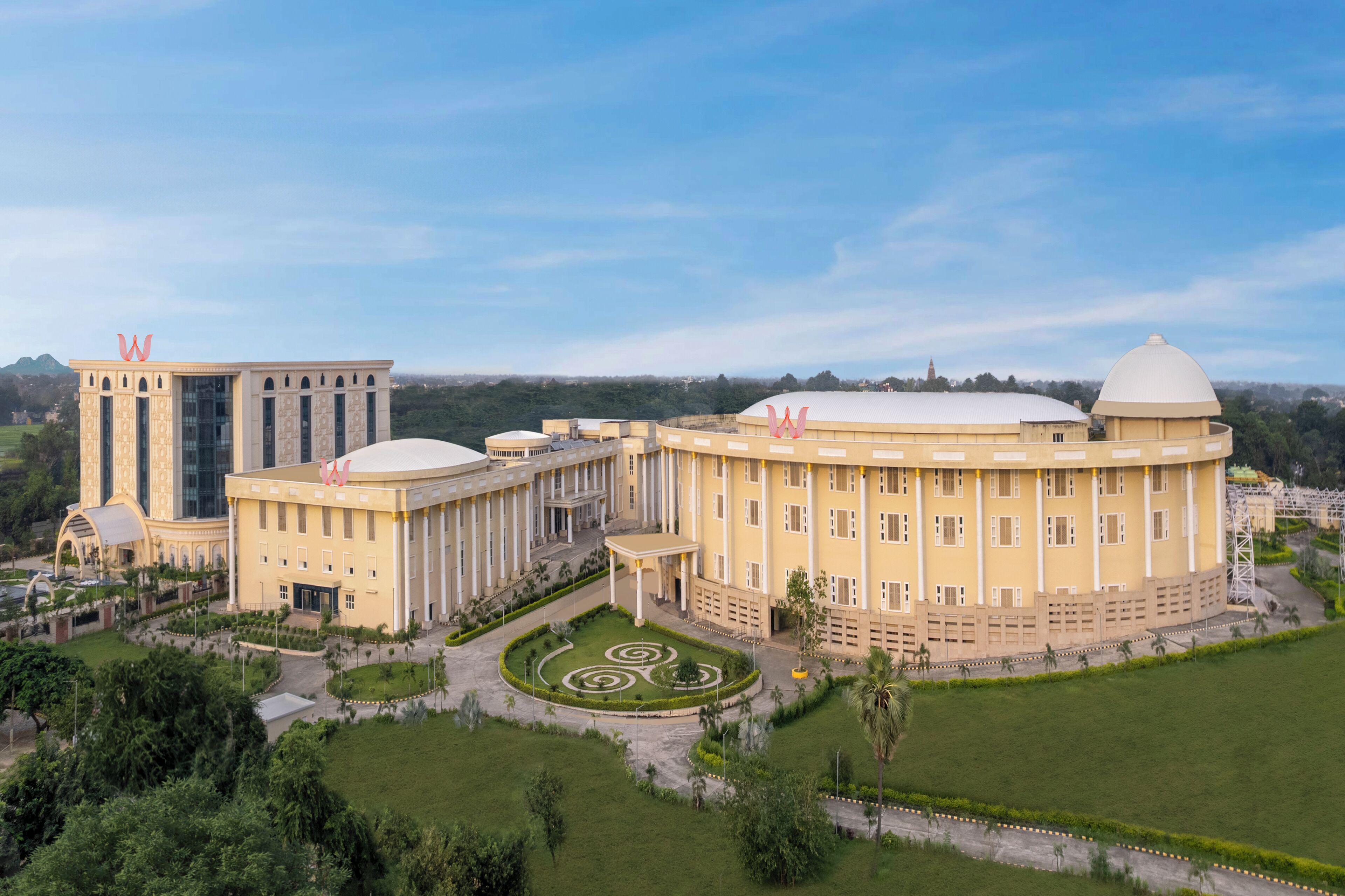 A large, yellow building with a dome and a tall tower, surrounded by a well-maintained garden and pathways.