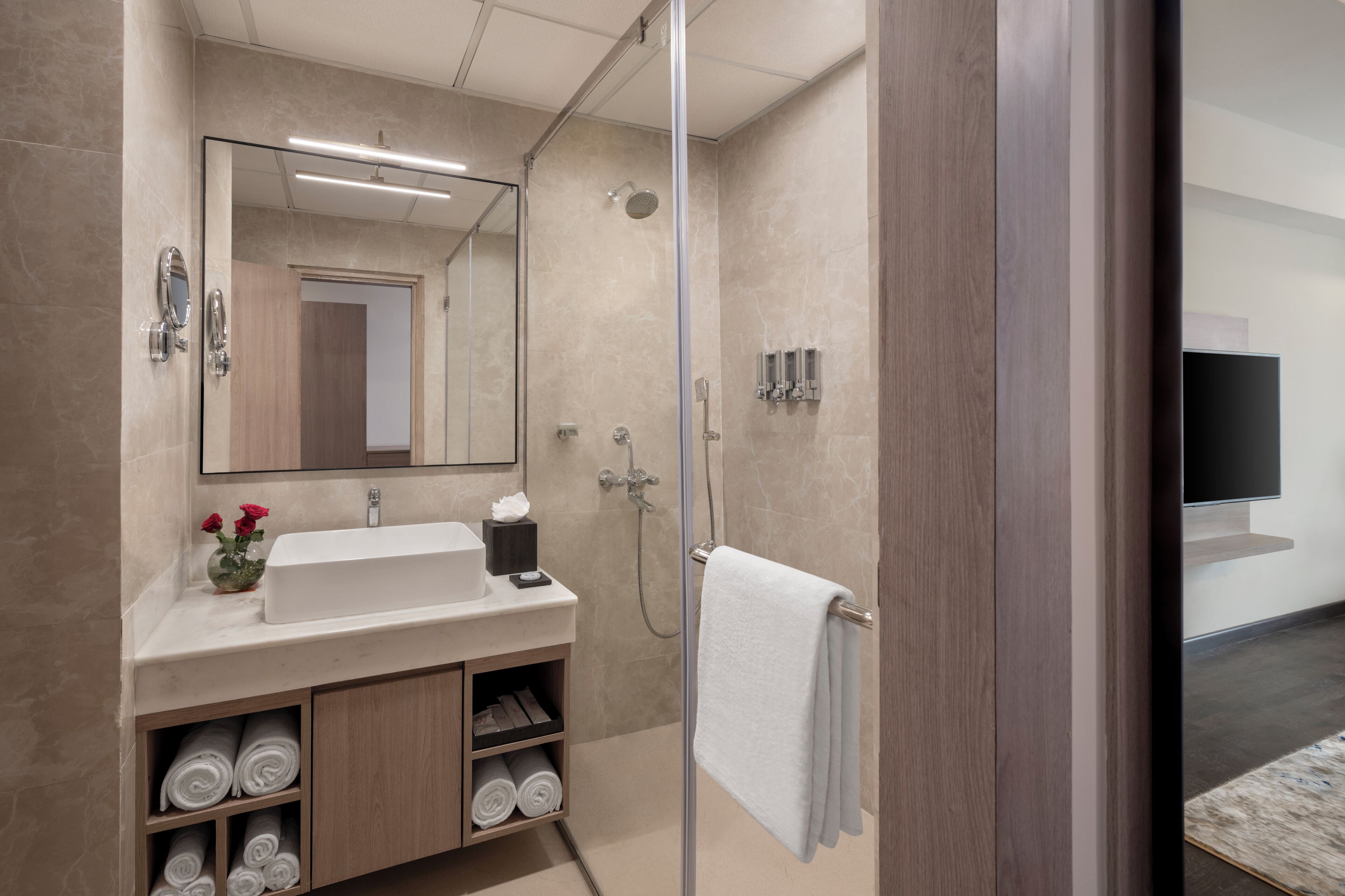 A modern bathroom with a glass shower enclosure, a sink with a mirror, and a towel rack.