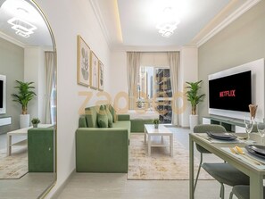 A modern living room with a green sofa, a flat-screen TV, and a dining area with a table set for two. - Zapbed House-mag 209 (Dubai)