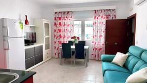 A compact living space with a kitchenette, dining area, and a teal sofa.