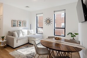 A modern living room with a sofa, a dining table, and a large window.