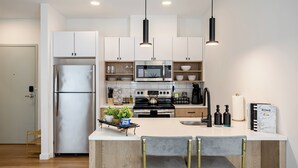 A modern kitchen with white cabinets, stainless steel appliances, and a central island with bar stools.