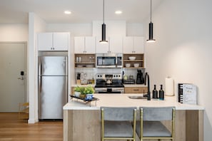 A modern kitchen with white cabinets, stainless steel appliances, and a central island with bar stools.