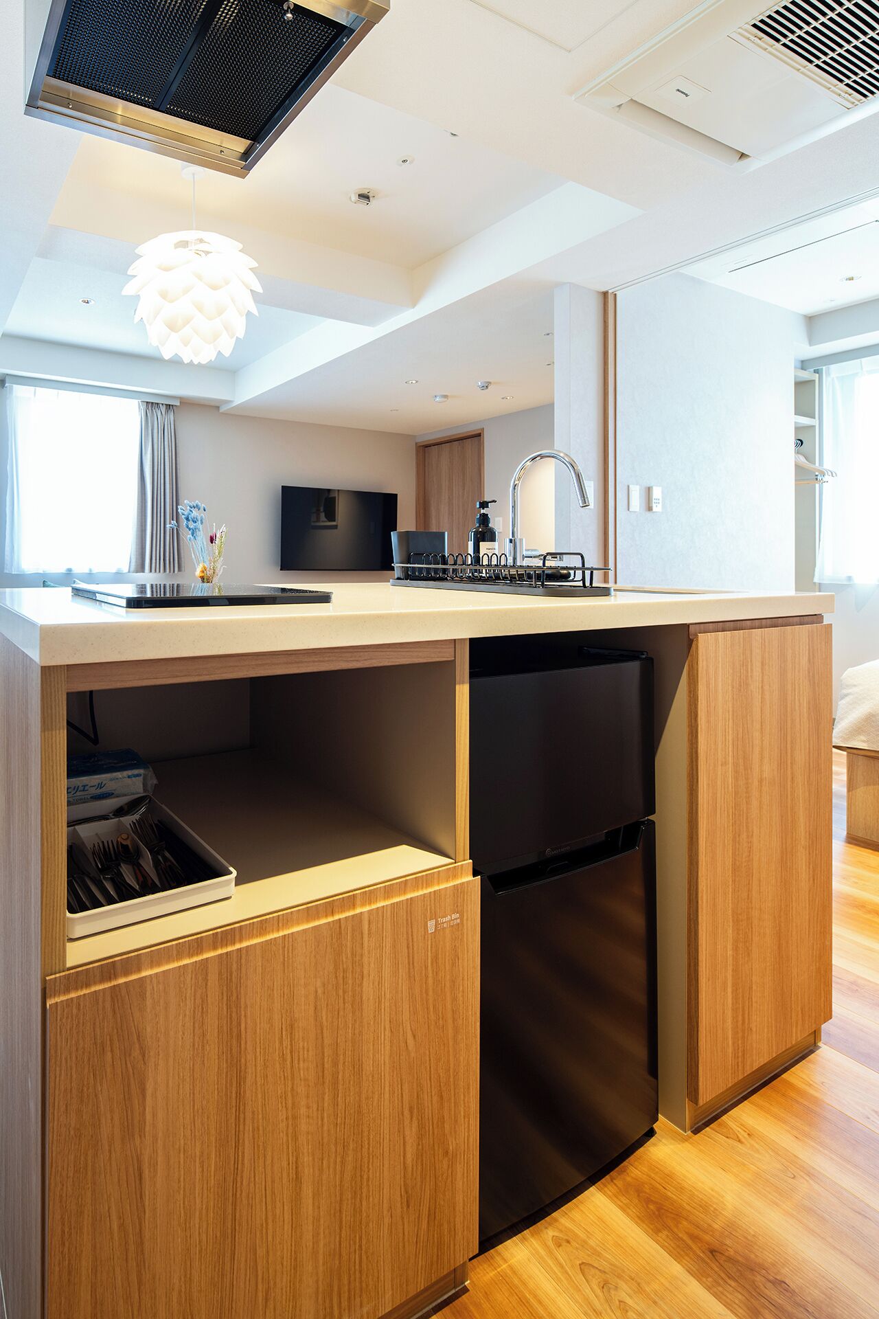 A modern kitchen with a built-in dishwasher, wooden cabinetry, and a pendant light.