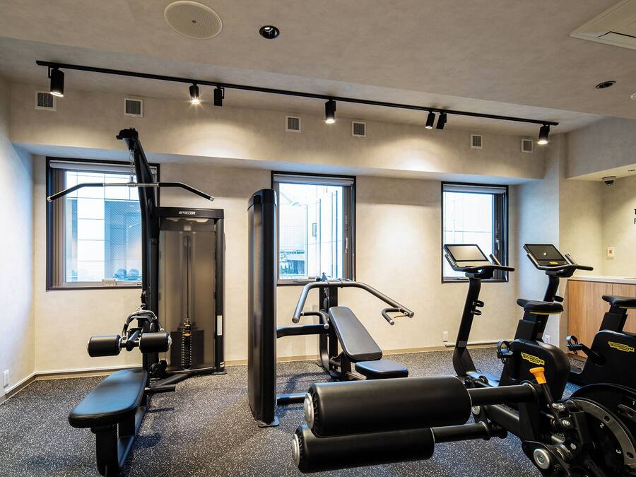 Ein Fitnessstudio mit Trainingsgeräten, großen Fenstern und einer Wand mit Text.