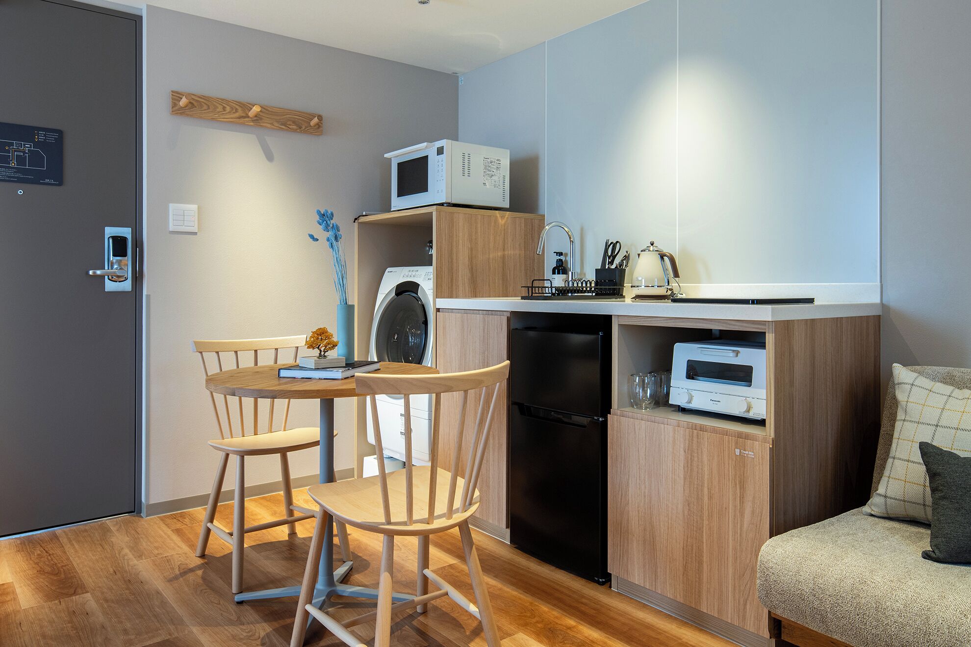 Una cocina compacta equipada con microondas, tostadora y lavavajillas, un comedor con mesa y sillas, y un sofá.