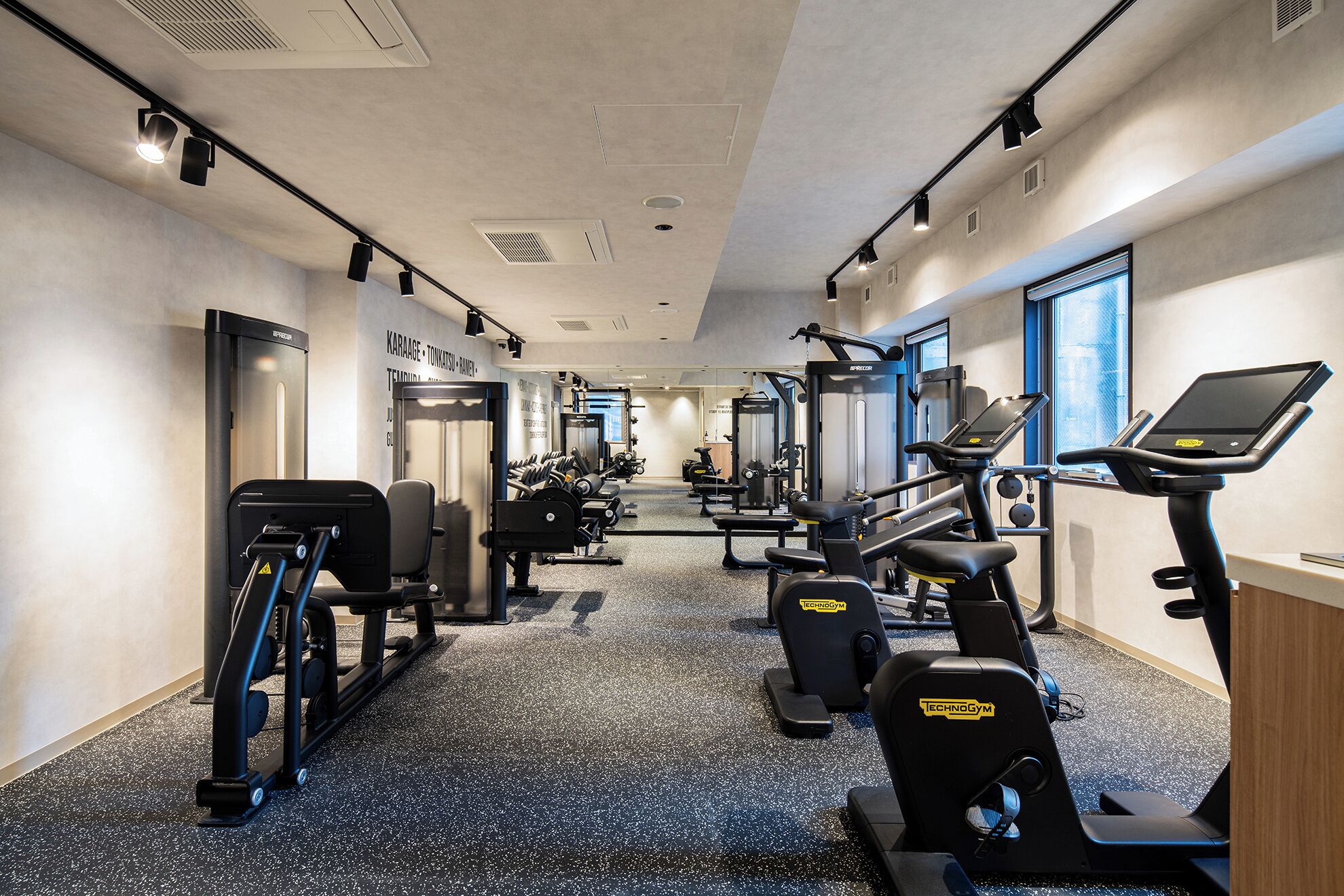 A gym with cardio equipment, weight machines, and a mirrored wall.