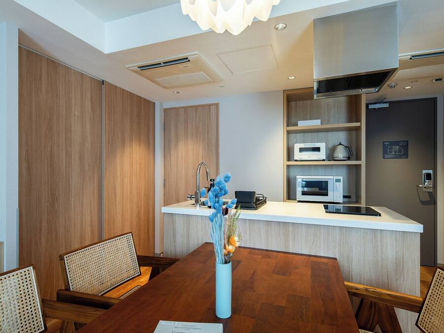 A modern kitchen with built-in appliances, a dining area with a wooden table and chairs, and a decorative vase with blue flowers.
