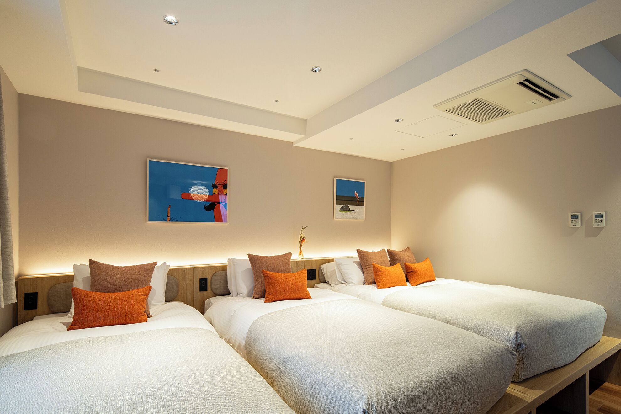 Ein Hotelzimmer mit zwei Betten, einem Deckenventilator und zwei Wandklimaanlagen.