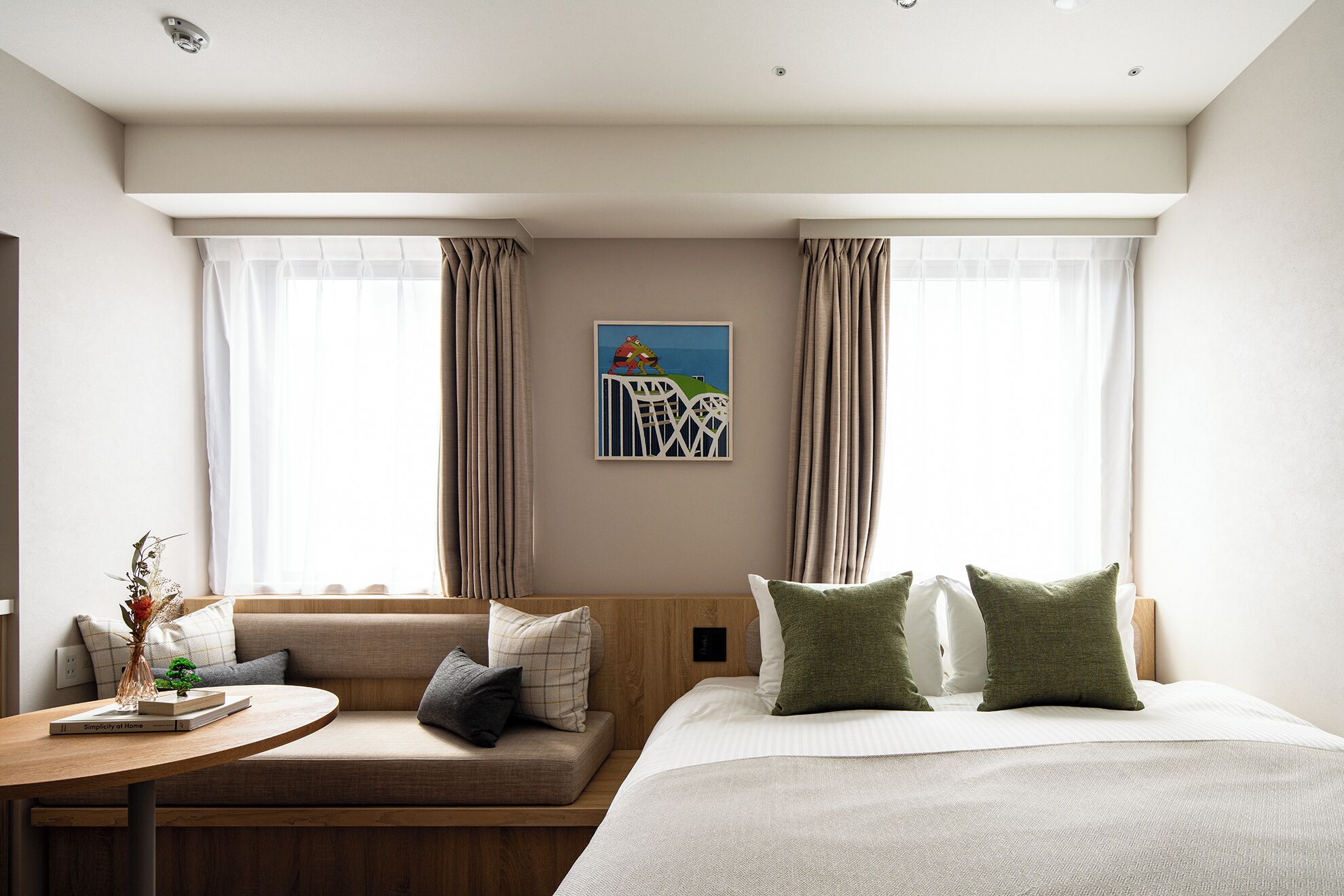 A hotel room with a bed, a sofa, a small table, and a painting on the wall.