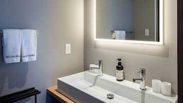 A modern bathroom with a large mirror, two sinks, and a towel rack.