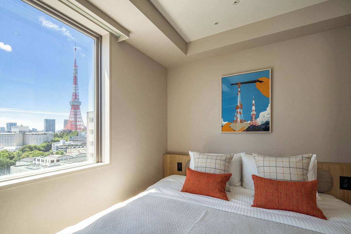 Quarto de hotel com uma grande janela que oferece vista para a paisagem urbana, incluindo uma torre imponente.