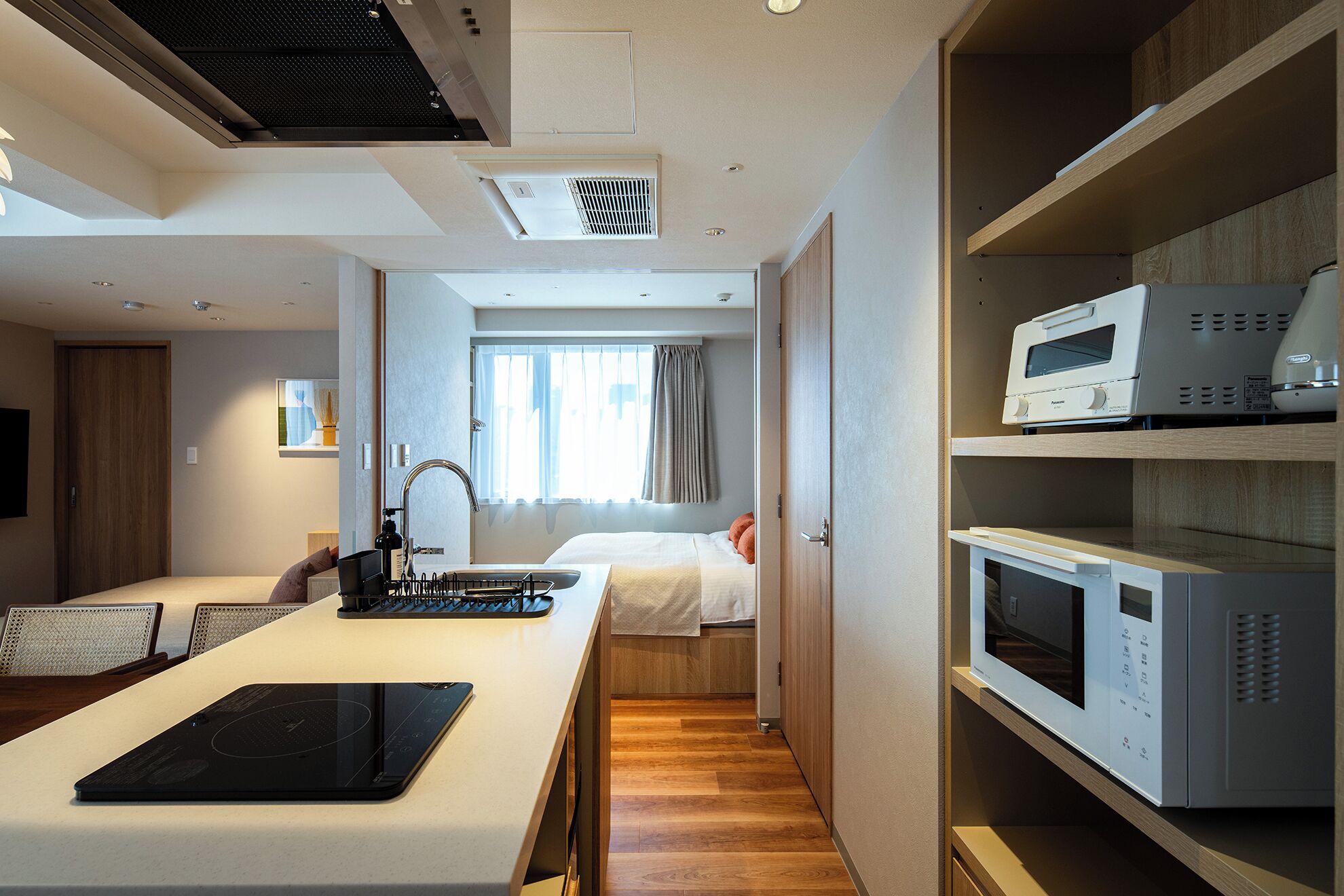Una habitación de hotel moderna con kitchenette, comedor y cama.