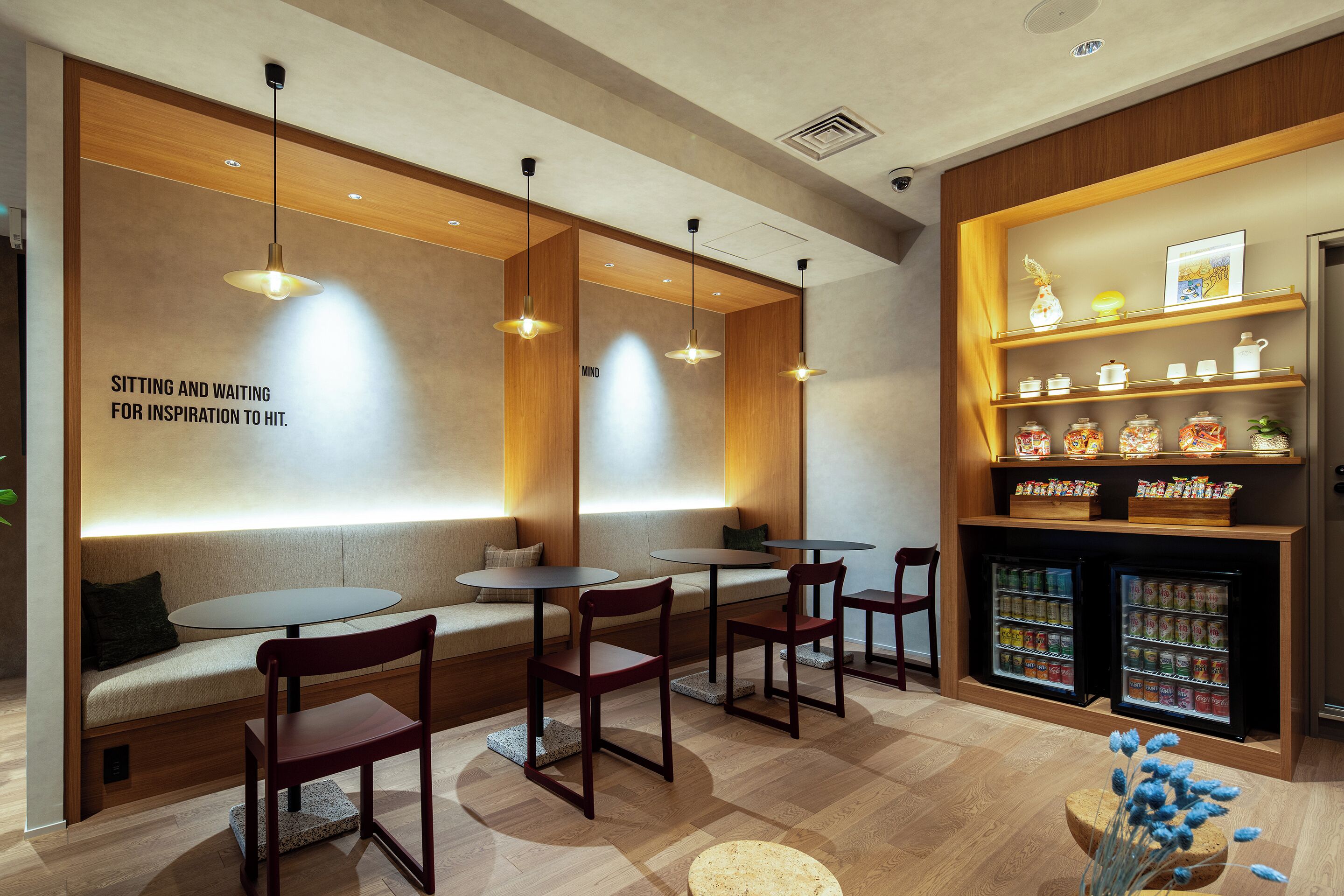 A seating area with tables and chairs, a wall with a motivational quote, and a shelf with snacks and a refrigerator.
