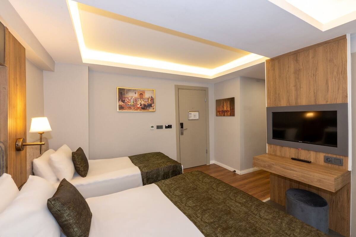 Une chambre d’hôtel avec deux lits, une télévision, un tableau et une porte avec une pancarte.
