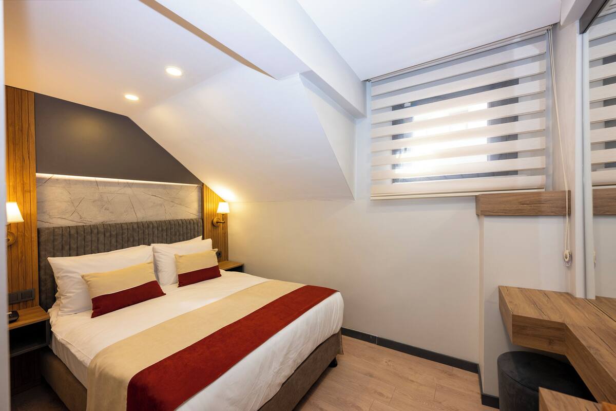 Une chambre d’hôtel moderne avec un grand lit, un bureau et un plafond en pente.