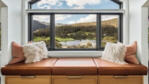 A room with a large window offering a view of a landscape with hills and a bridge. - Luxury Mountain Chalet one of Crackenback's best (Crackenback)