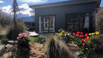Una casa moderna con un patio, rodeada de diversas plantas y flores.