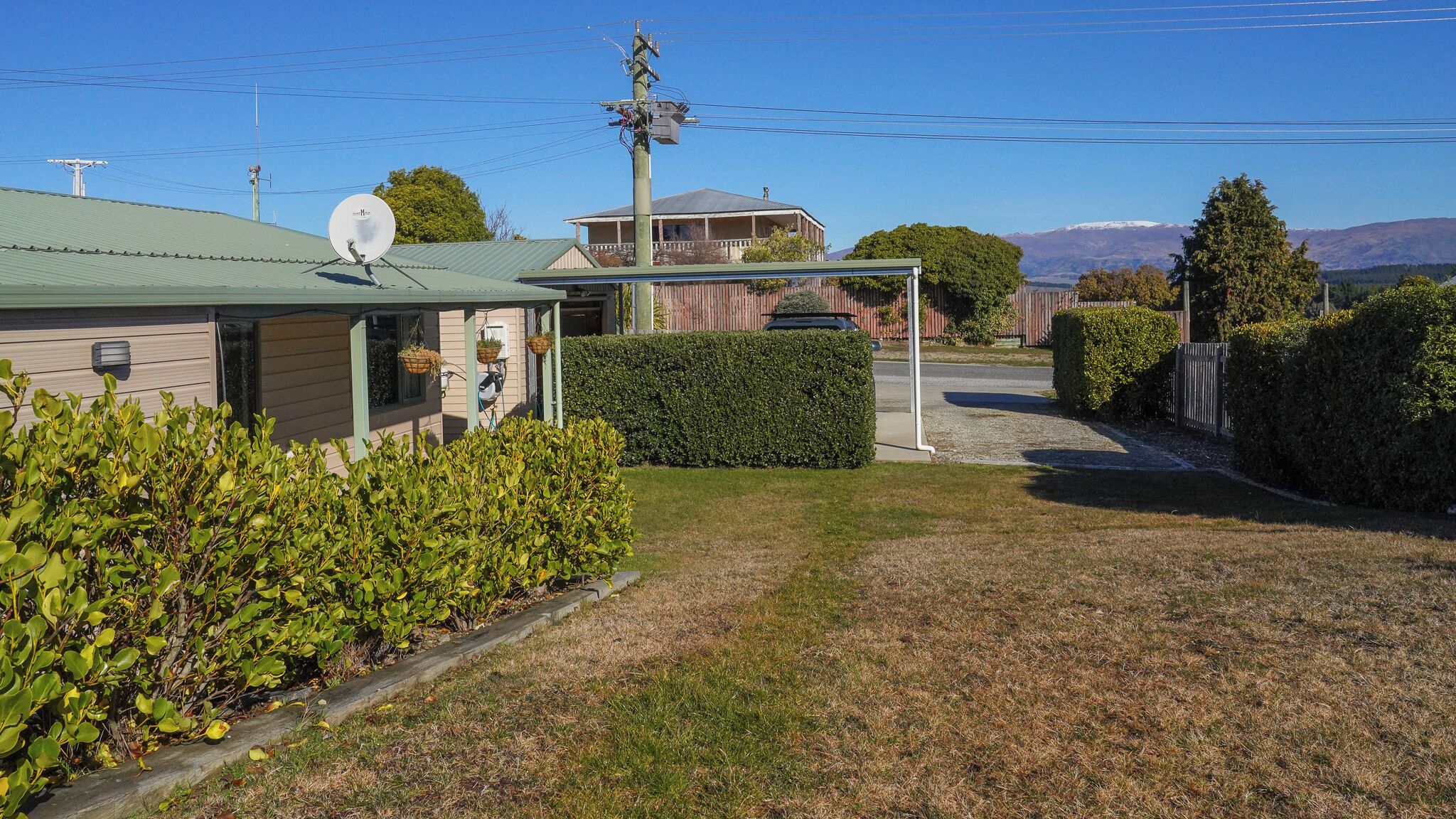 A residential area with a house, a satellite dish, and a well-maintained lawn.