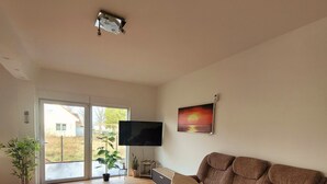 Ein Wohnzimmer mit einer Couch, einem Couchtisch, einem Fernseher und einem Bild an der Wand.