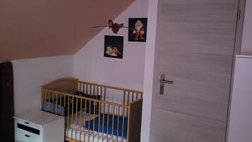 Une pièce avec un berceau, une porte, un ventilateur de plafond et des décorations murales.