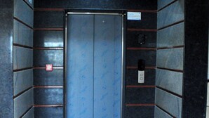 Un ascensor con puerta azul, rodeado de paredes de piedra oscura con detalles rojos.