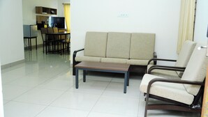 Una sala de estar con sofá, dos sillones, una mesa de centro y una zona de comedor con mesa y sillas.
